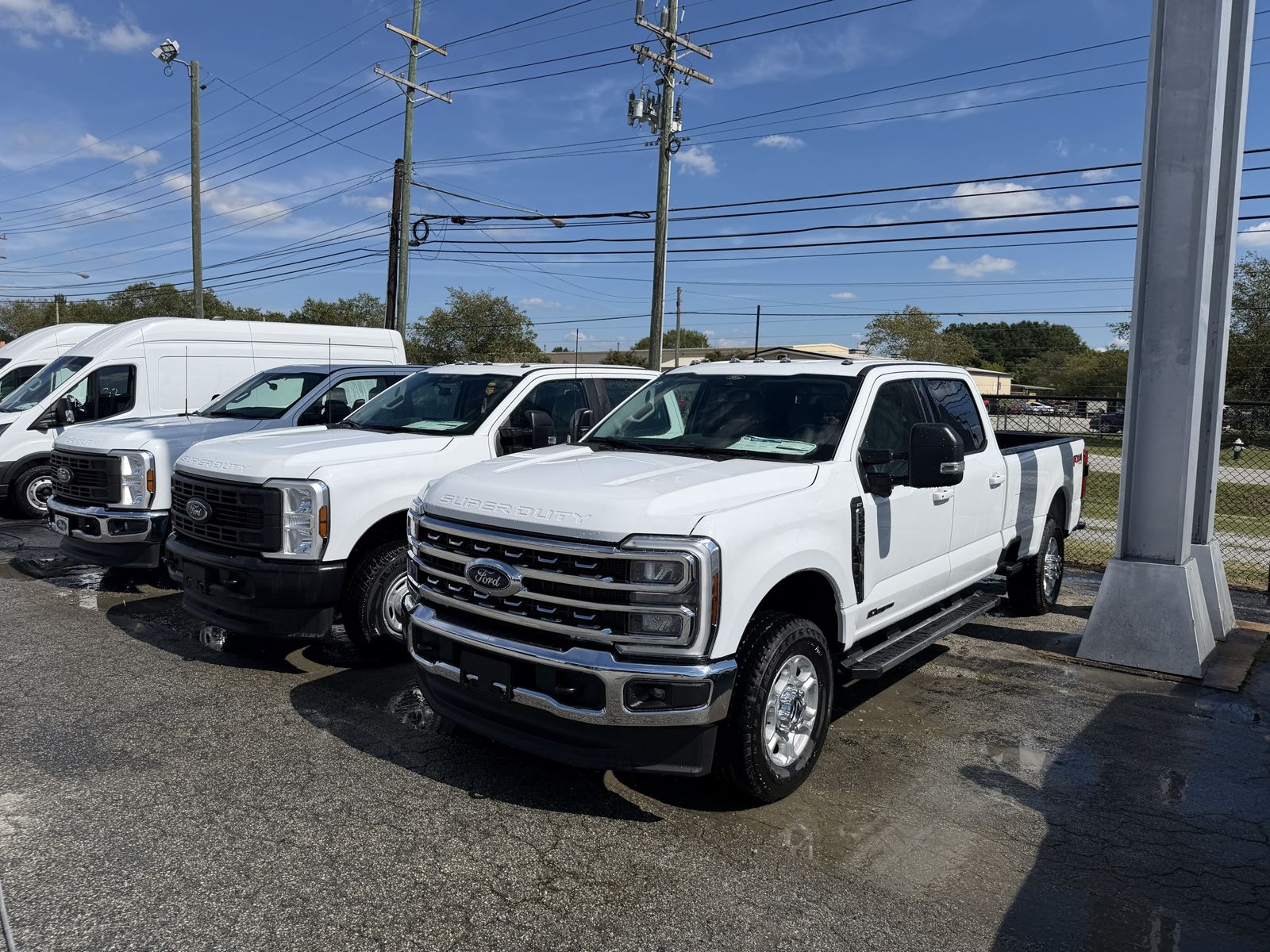 Freshly washed white pickup trucks lined up on a dealer lot